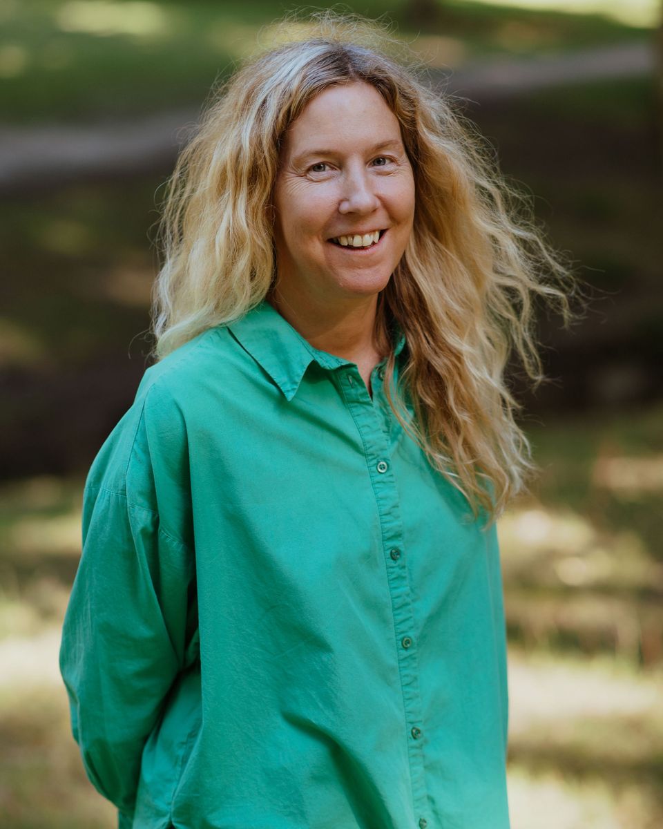 Anne-Marie Watson smiling in dappled woodland light